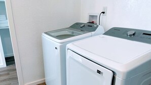 A laundry area with two front-loading washing machines and a dryer.