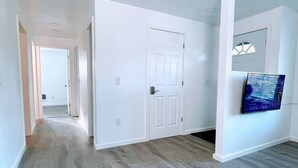 A hallway with a wooden floor, white walls, and a door with a handle.