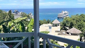 A view from a balcony overlooking a cruise ship, palm trees, and a coastal cityscape. - Humming Bird Holiday Retreat (Ocho Rios)