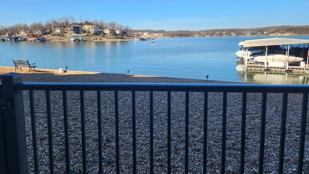 Une vue sur le lac, avec un quai, un banc et un bâtiment situé de l’autre côté de l’eau.