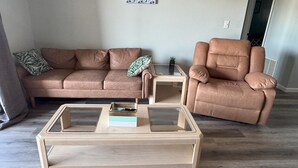 Un salon avec un canapé en cuir marron, un fauteuil assorti et une table basse en bois.