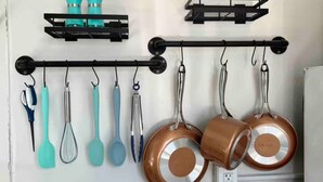 Una cocina con utensilios y ollas colgadas en un perchero.