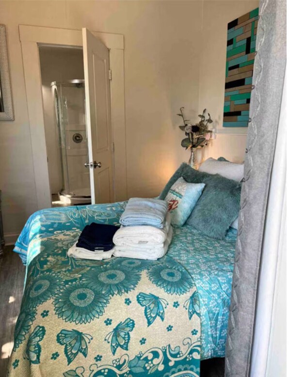 A bedroom with a bed, a shower, and a wall-mounted artwork.