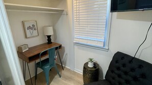 A compact living space with a desk, chair, and a black tufted sofa.