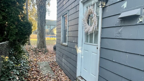 A house with a white door, a wreath on the door, and a concrete step leading to the door.