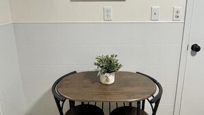 A dining area with a round wooden table, two black chairs, and a small potted plant.