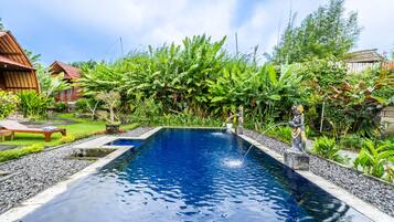 Una piscina al aire libre, sillones reclinables de piscina