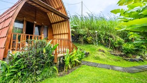 A wooden cabin with a sloped roof, surrounded by lush greenery and a stone pathway. - KINTAMANI Paradise (Kintamani)