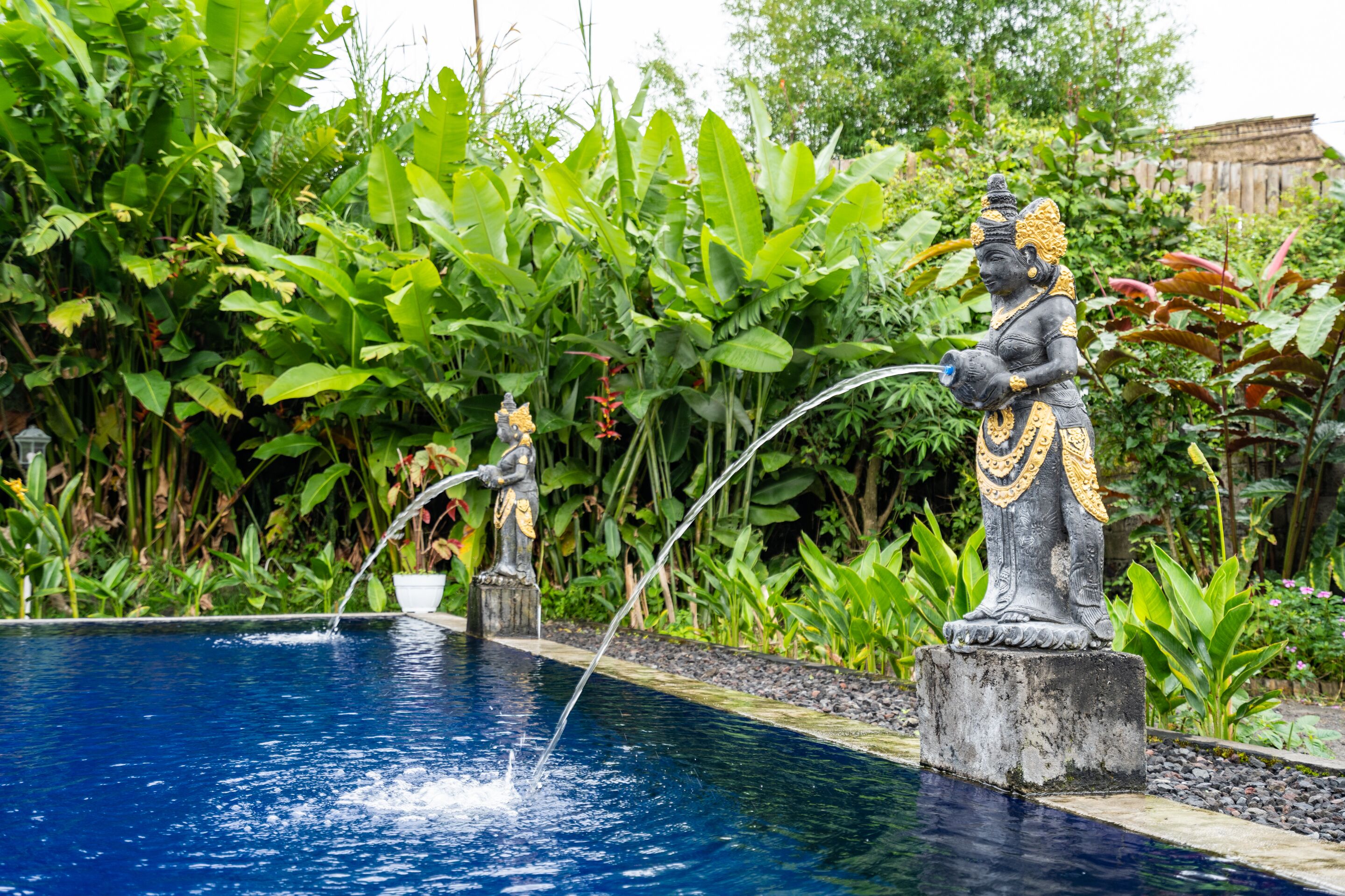 Una piscina con estatuas y abundante vegetación.