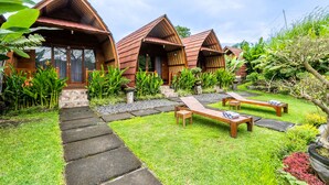 A row of wooden cabins with a stone pathway leading to a seating area. - KINTAMANI Paradise (Kintamani)