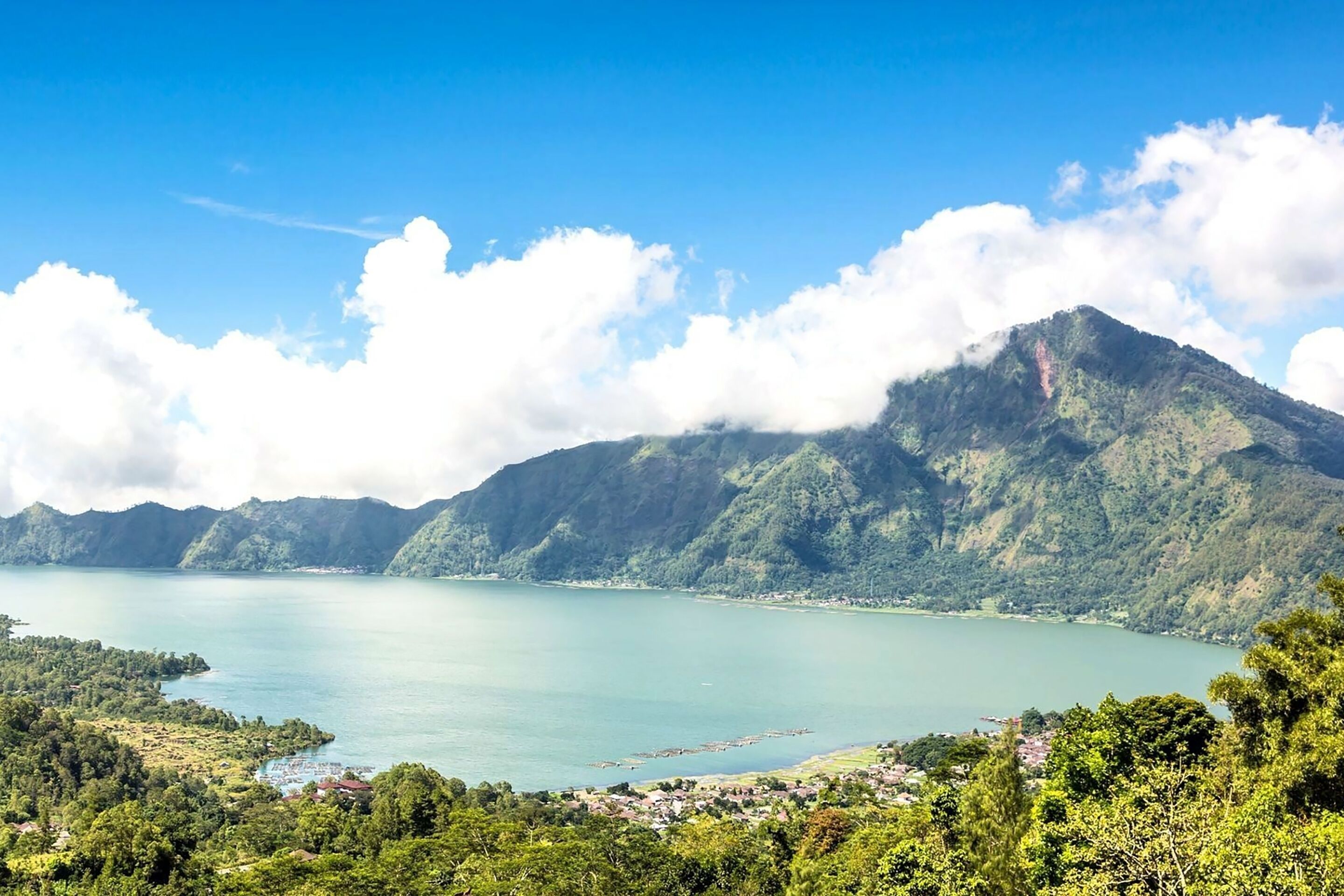 Un paisaje costero con una montaña, un lago y un pueblo.