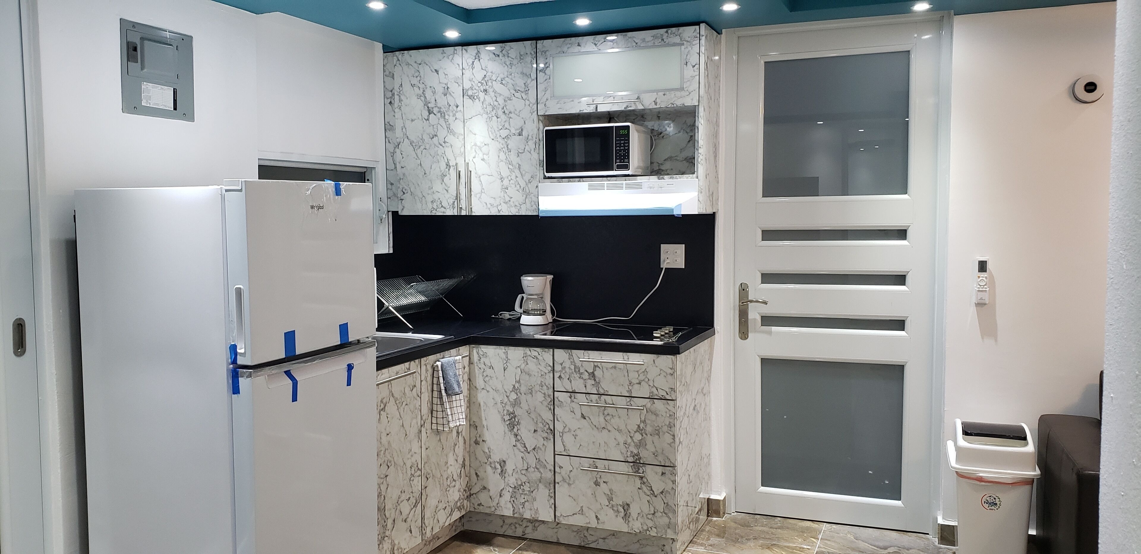 Eine moderne Küche mit eingebauter Mikrowelle, einer Kaffeemaschine und einem Kühlschrank.