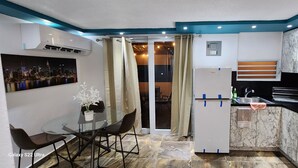 Una cucina compatta con un tavolo da pranzo in vetro, un frigorifero, un forno a microonde e un lavandino.