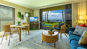 A modern living room with a dining area, a large window with a view of the ocean, and a cozy seating arrangement.