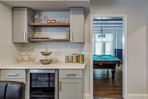 A kitchen with white cabinetry, a countertop with glassware, a coffee maker, and a refrigerator.