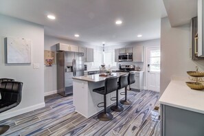 A modern kitchen with a central island, bar stools, and a refrigerator.