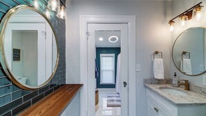 A bathroom with a wooden vanity, a large mirror, and a sink with a marble countertop. - Port Clinton 4 Bdrm Luxury-2 blocks from beach (Port Clinton)