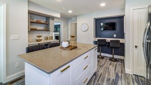 A modern kitchen with a central island, built-in shelves, a clock, and a TV mounted on the wall. - Port Clinton 4 Bdrm Luxury-2 blocks from beach (Port Clinton)