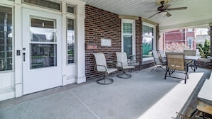 A covered patio with a brick wall, white-framed windows, and a ceiling fan. - Port Clinton 4 Bdrm Luxury-2 blocks from beach (Port Clinton)