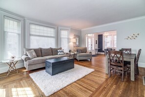 A living room with a sofa, coffee table, and dining area with chairs.