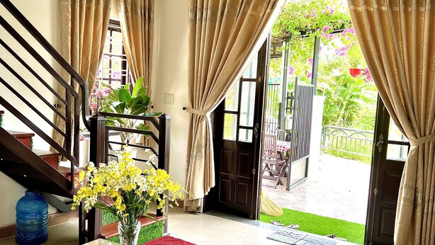 A spacious living area with a glass-top table, a sofa, and a staircase. - Ngo Family Apartment (Da Nang)