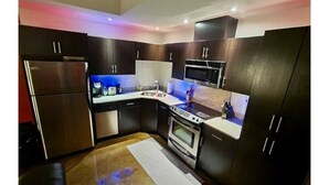 A compact kitchen with dark cabinets, stainless steel appliances, and a small countertop. - 2bedroom/2washroom condo close to everything + Free Parking (Calgary)