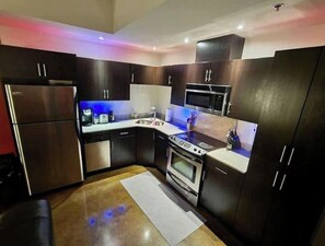 A compact kitchen with dark cabinets, stainless steel appliances, and a small countertop.