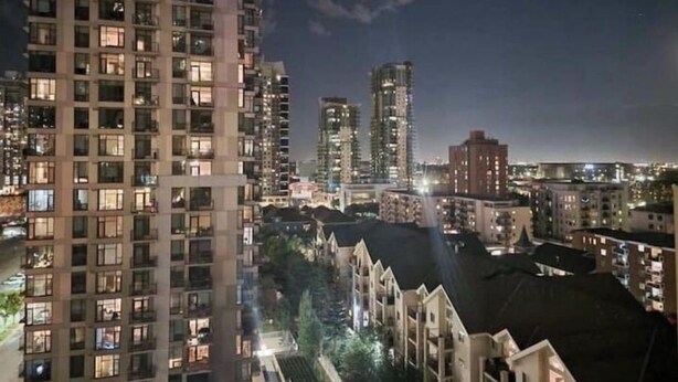 A high-rise building with multiple floors and balconies, surrounded by other buildings. - 2bedroom/2washroom condo close to everything + Free Parking (Calgary)