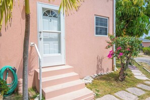 A house with a white door, a small window, and a set of concrete steps leading to the door.