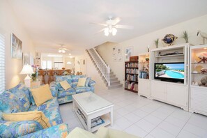 A living room with a sofa set, a coffee table, a television, and a bookshelf.