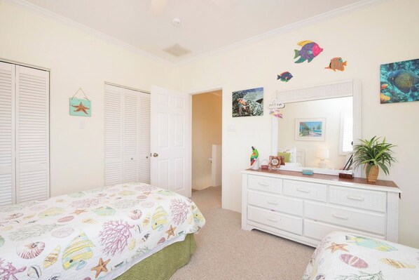 A bedroom with two beds, a dresser, and a mirror.