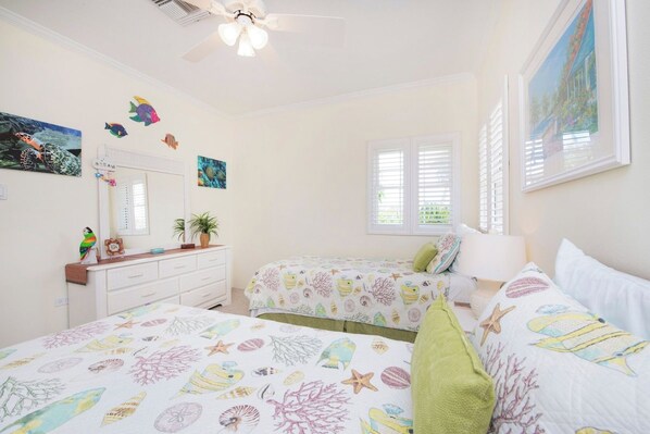 A bedroom with two beds, a dresser, a mirror, and a ceiling fan.