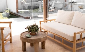 Relax in a serene outdoor space with a sofa, table, and chair, surrounded by lush greenery.