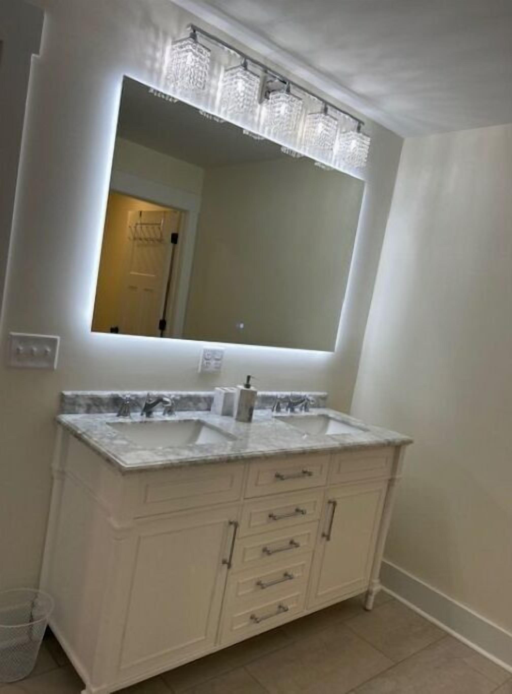 A bathroom with a double sink vanity, a large mirror, and a towel rack.