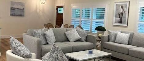 A spacious living room with a ceiling fan, a sofa set, and a coffee table.