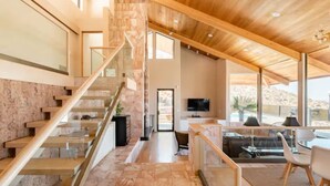 Un interior moderno con una escalera, un comedor y un televisor.
