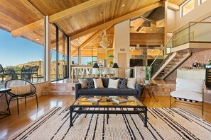 Un vaste espace de vie doté d’un haut plafond, d’un grand canapé, d’une table basse et d’un escalier menant à un niveau supérieur.