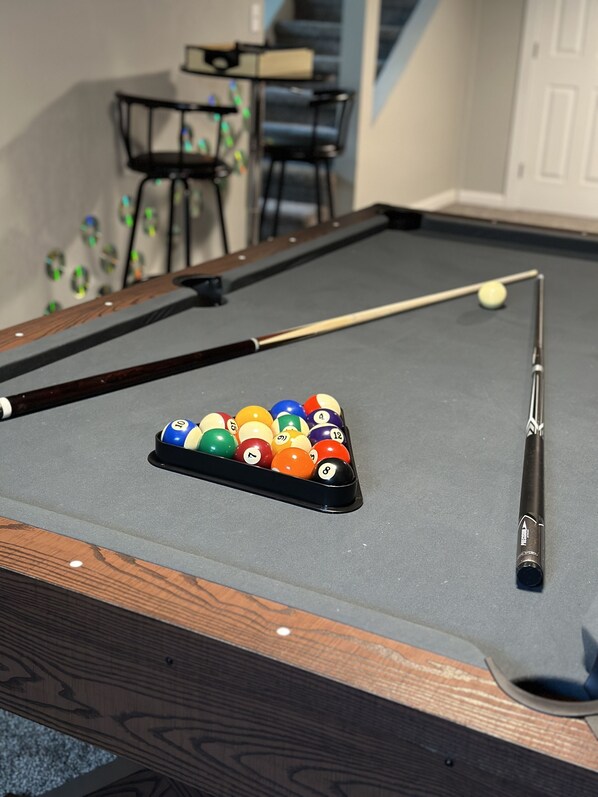 Une table de billard avec un jeu de billes et un queue de billard.