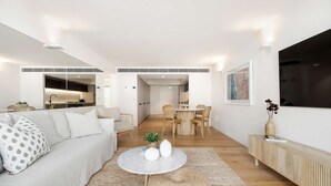 A modern living room with a sofa, coffee table, and dining area. - Bondi Breeze (Bondi)