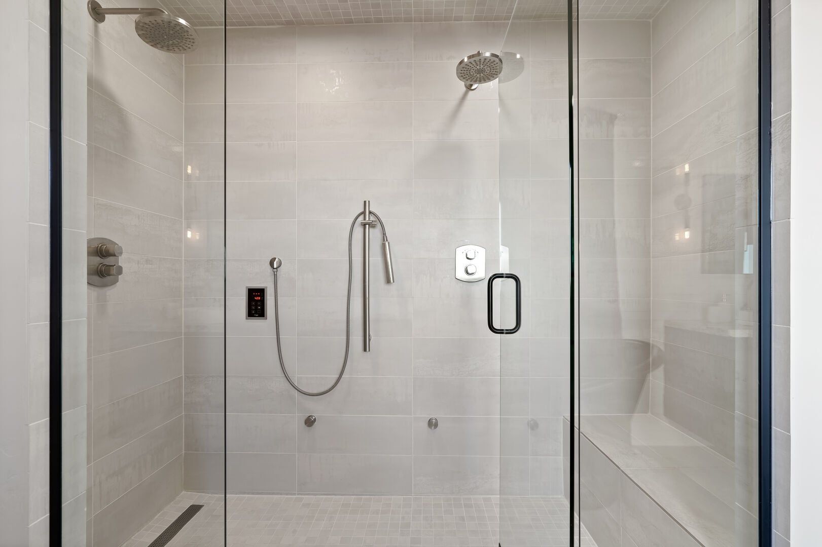 A modern shower with a handheld showerhead, a fixed showerhead, and a control panel.