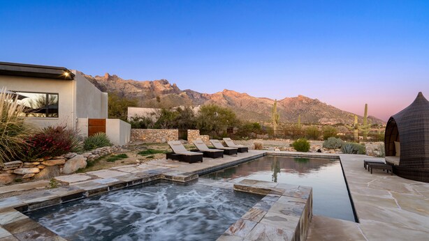 Un espace piscine extérieur moderne, doté d’un jacuzzi, de chaises longues et d’une terrasse en pierre.