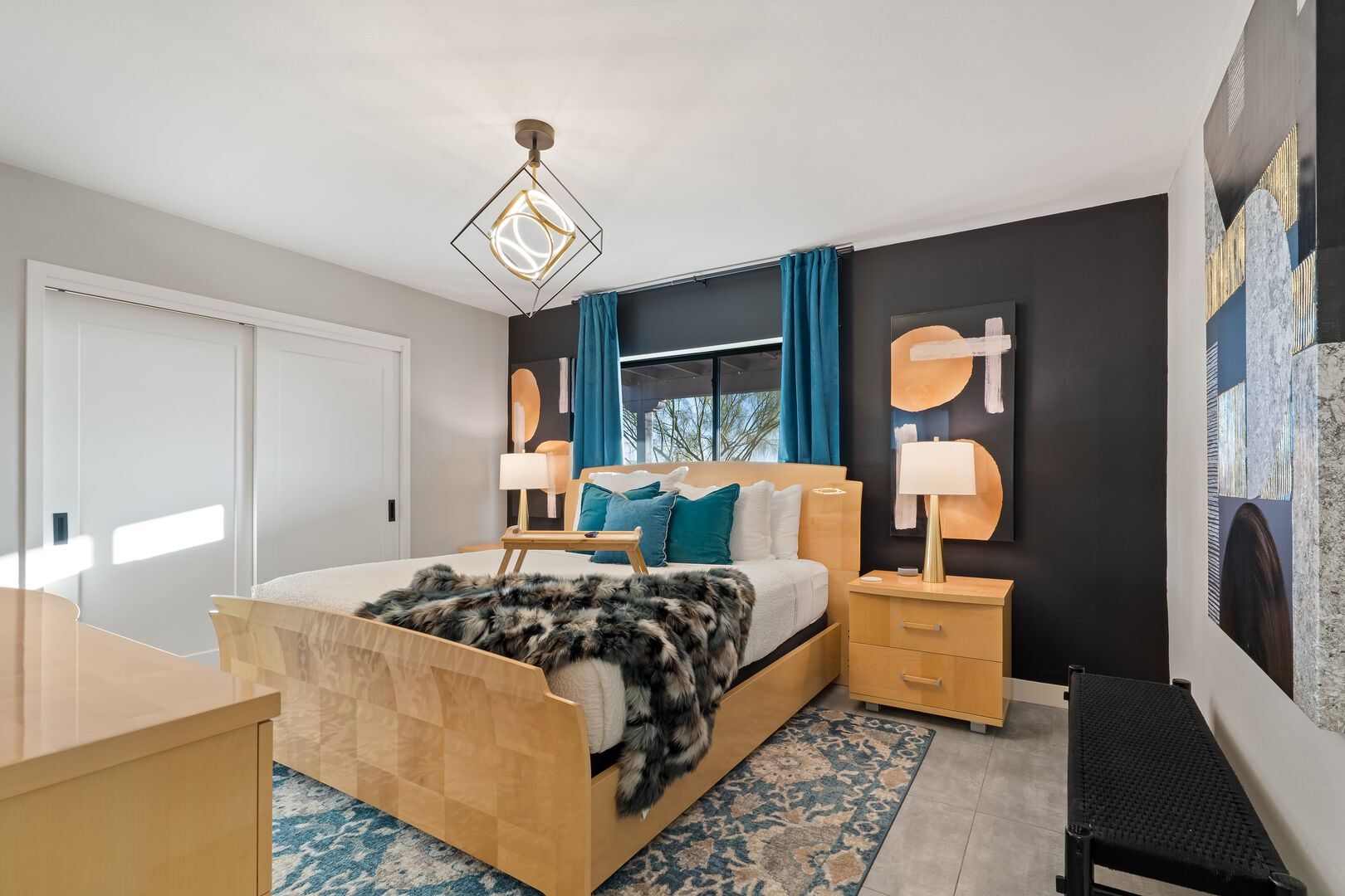 A modern bedroom with a wooden bed, a desk, a standing lamp, and a large window with curtains.