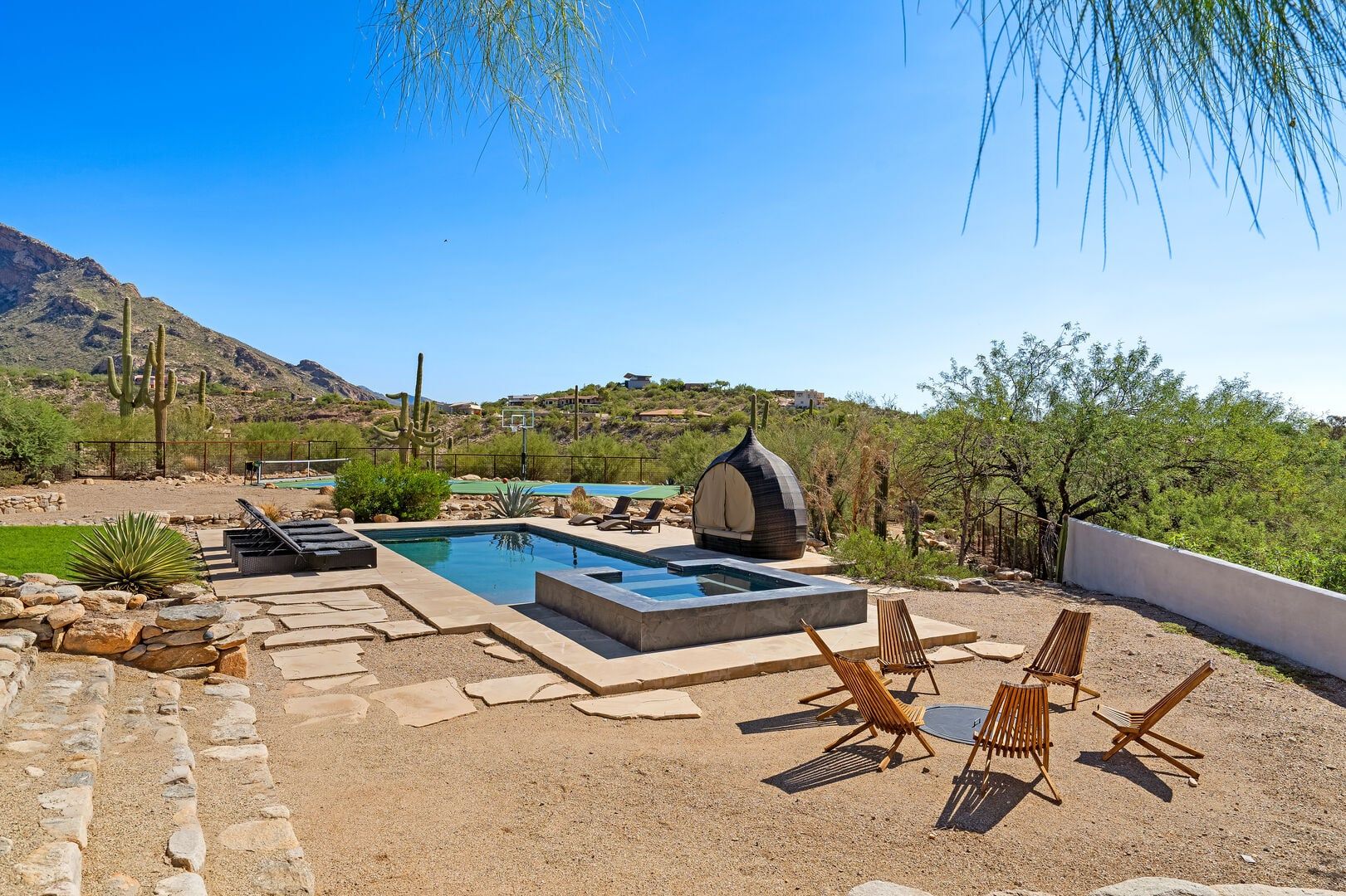 Un área de piscina con sillones de descanso, un jacuzzi y vistas a un paisaje montañoso.