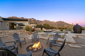 An outdoor patio with a fire pit, seating, and a view of mountains. - Catalina Clubhouse | Luxury Retreat in Tucson | Fieldtrip (Tucson)