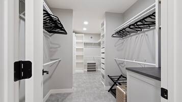 Un pasillo estrecho con paredes blancas, suelo de baldosas grises y un mueble de almacenamiento central con varios compartimentos.