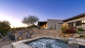 Un jardin avec un jacuzzi, des sièges en pierre et un espace patio.