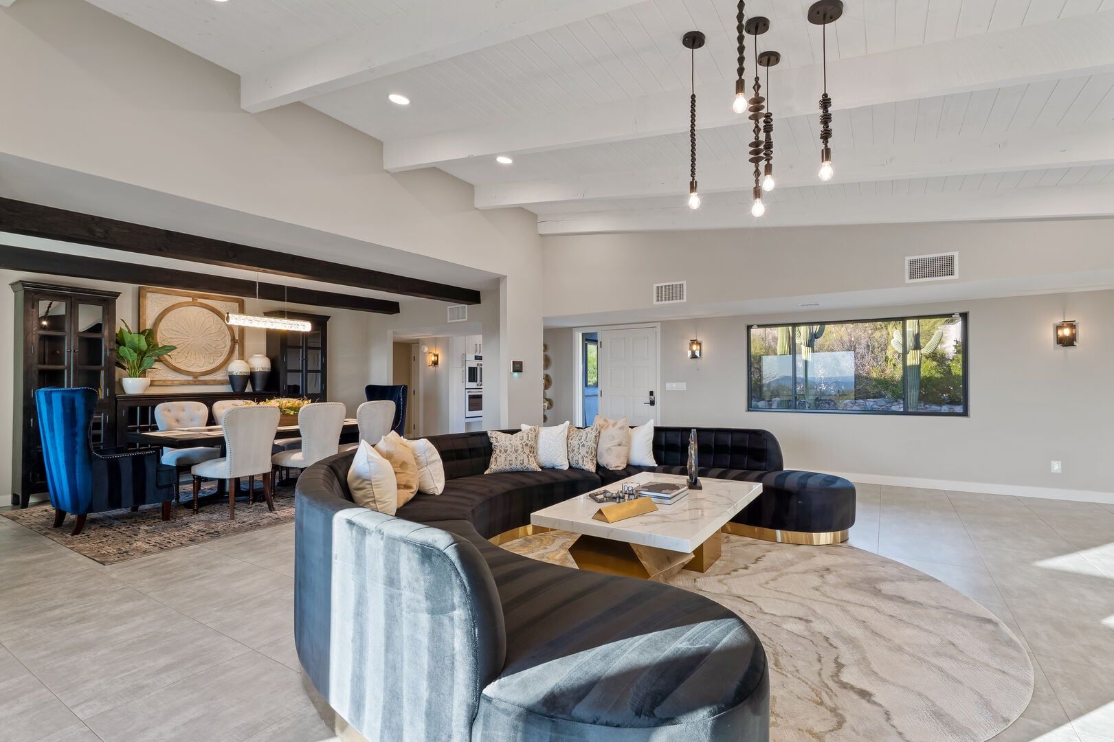 A spacious living area with a large sofa, a coffee table, and a dining area with chairs and a table.