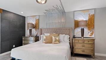 Un dormitorio moderno con una cama grande, dos mesitas de noche, un candelabro, arte abstracto en la pared y una pared con textura.
