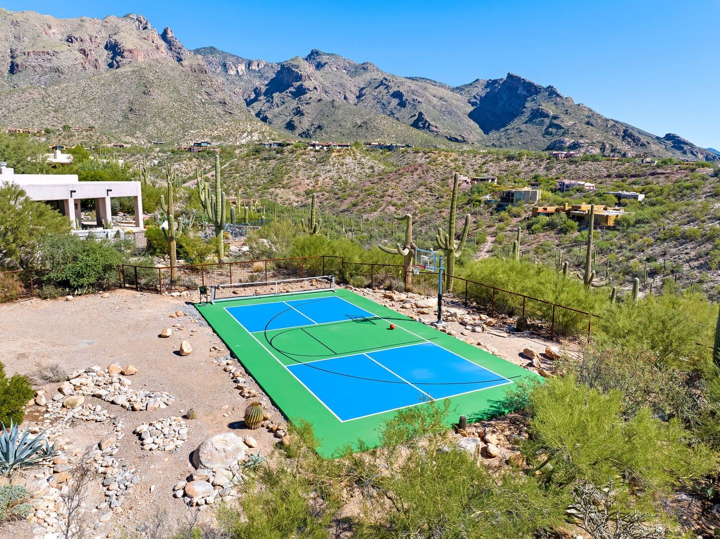 A basketball court with a mountainous backdrop, surrounded by cacti and sparse vegetation.