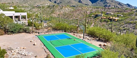 A basketball court with a mountainous backdrop, surrounded by cacti and sparse vegetation.